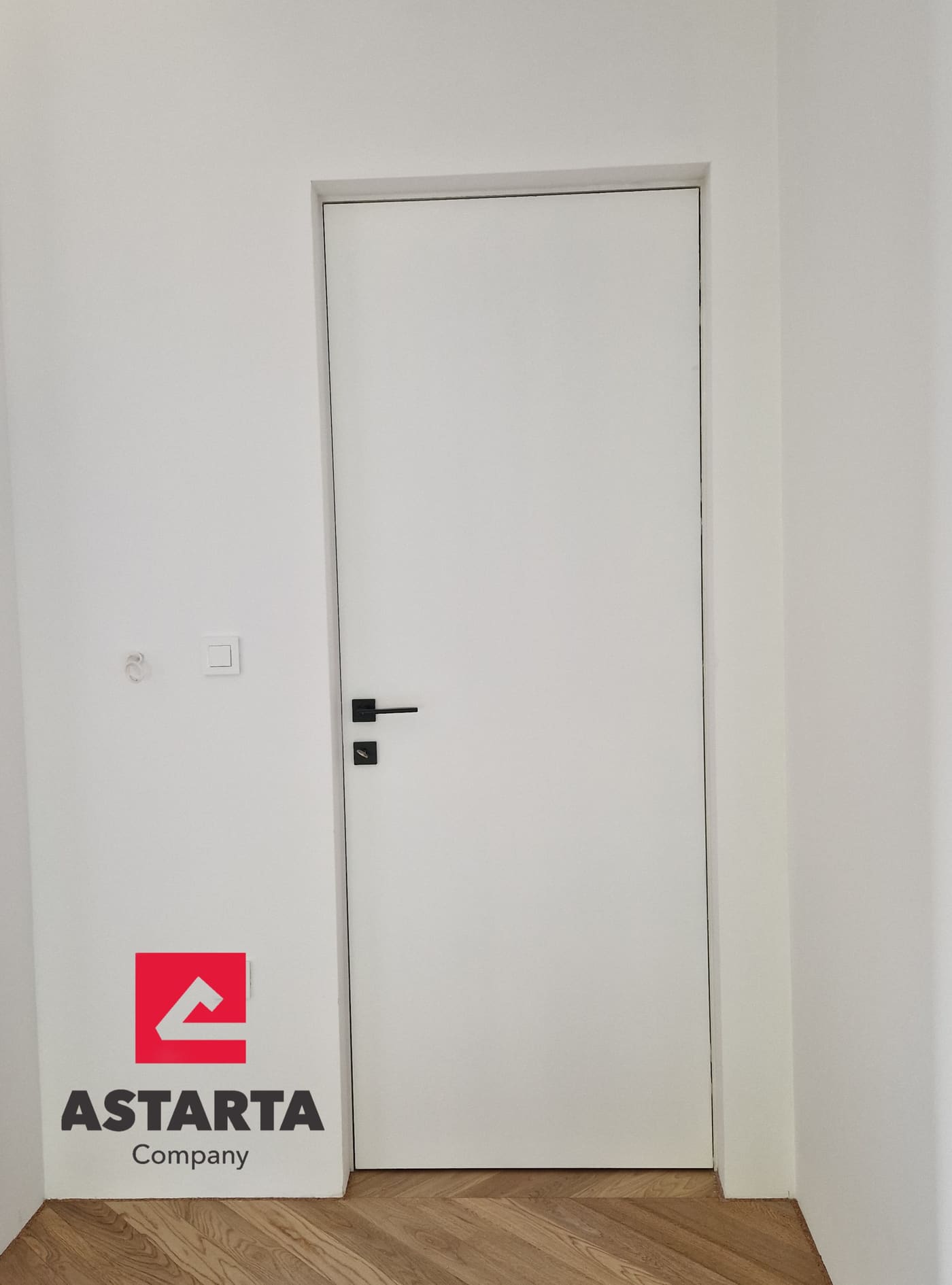 Bijela filomuro vrata s crnom kvakom u svijetloj sobi