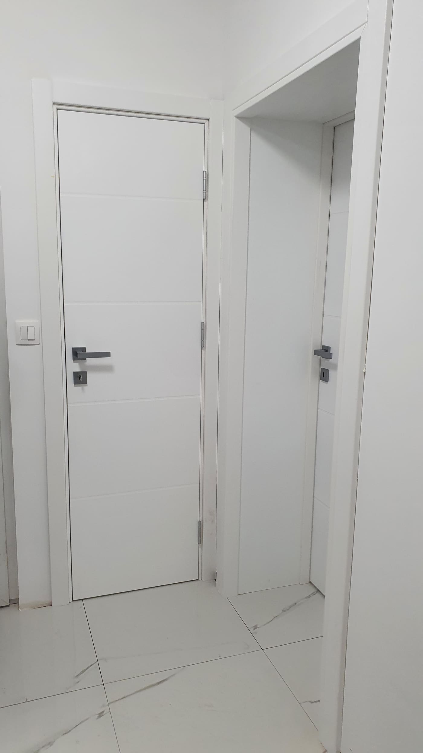 Dvoja bijela lakirana vrata s glatkom plohom uz mramorni pod