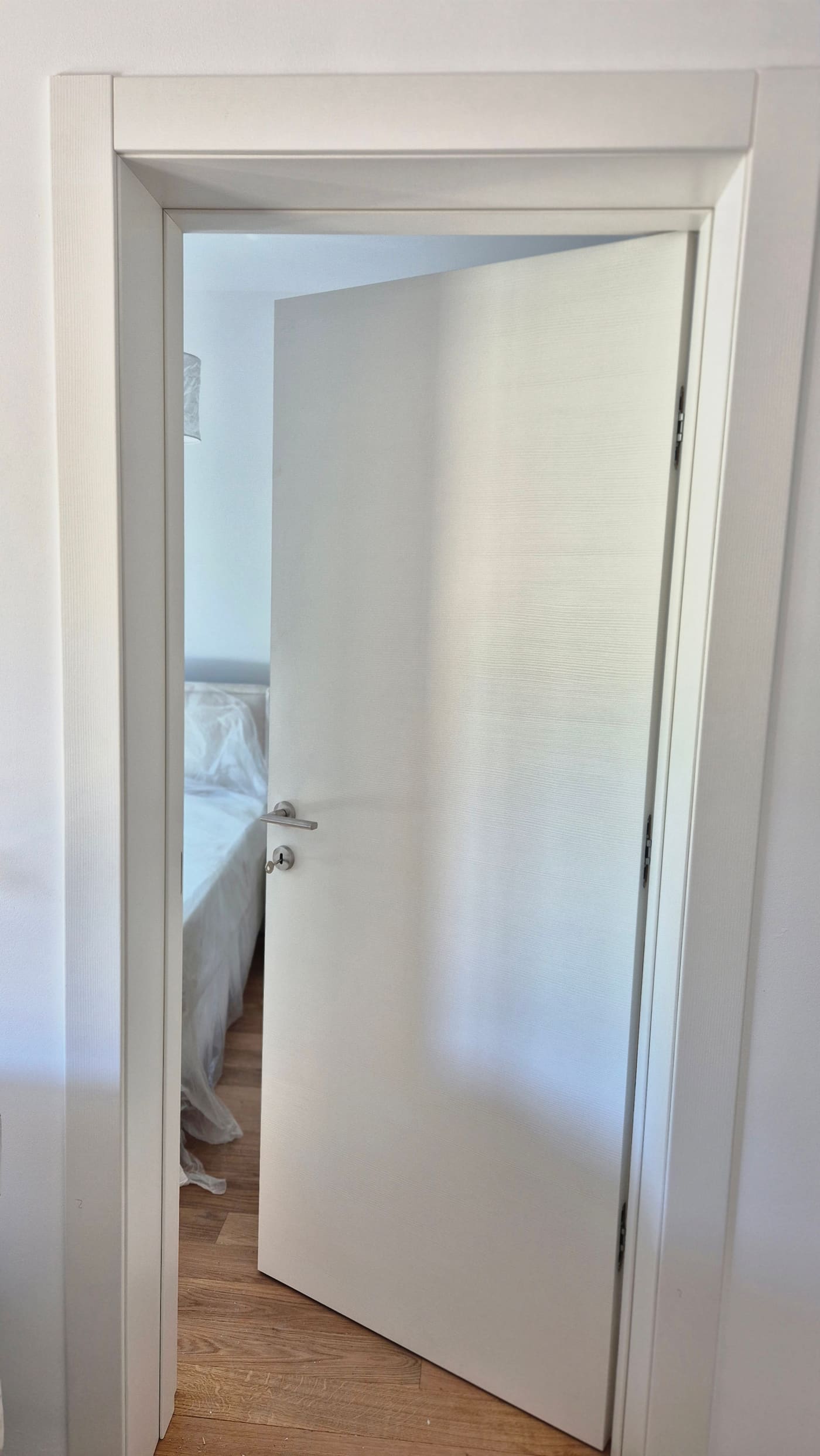 Bijela laminirana vrata otvorena prema spavaćoj sobi